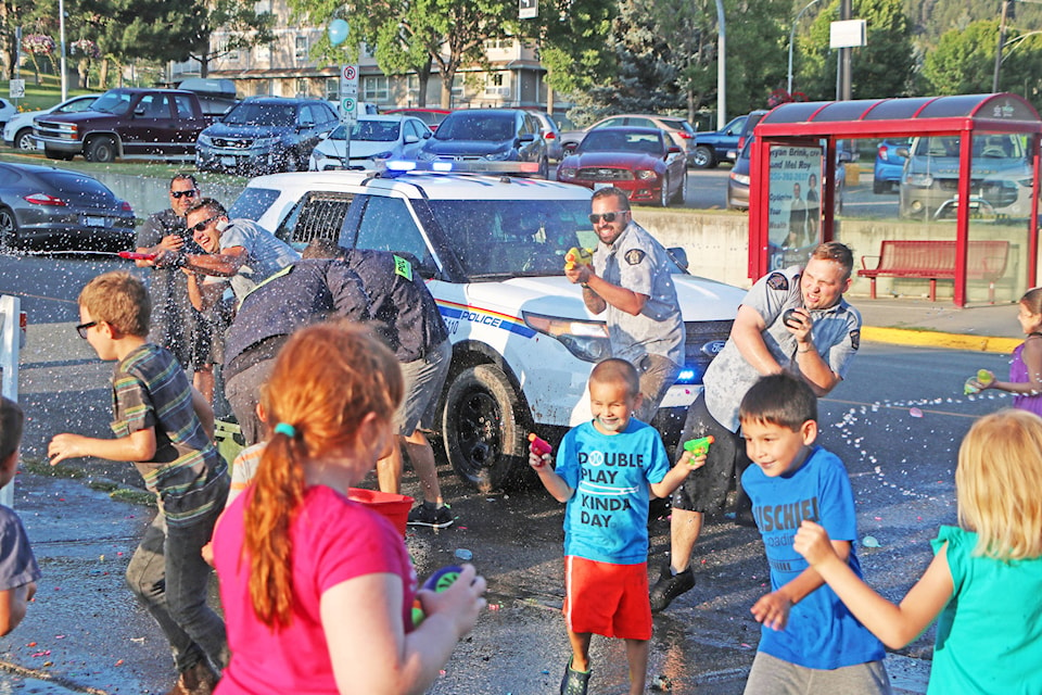 Patrick Davies photo Members of the Williams Lake RCMP Detachment valiantly attempt to hold the line as swarms of excited children assail them with water balloons and water guns at the end of the Boys and Girls Club of Williams Lake and District Street Party Wednesday evening downtown.