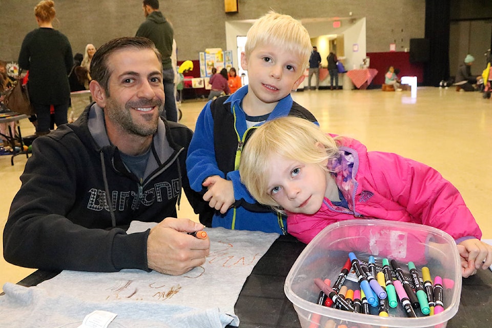 Rob Manarin (from left) smiles with his twin children Clark Manarin and Makenna Manarin as they make their own t-shirts at the 3 Year Old Round Up in the Gibraltar Room. Patrick Davies photo.