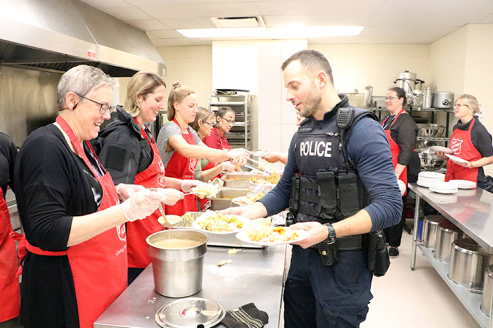 Patrick Davies photo Lyn Temple smiles as she spoons out some gravy onto a plate of food held by Constable Klassen at the Salvation Army’s Thanksgiving Lunch.