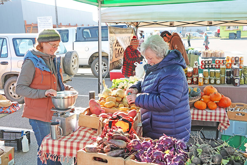 Stephanie Bird laughs as Charlee Mansel reaches into her coin purse to pay her for some fresh produce bought at 2019’s last Williams Lake Farmer’s Market. Patrick Davies photo.