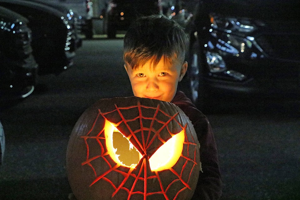 Beckett Kooger tests his freshly carved Jack’O’Lantern using his mom’s phone outside of Cariboo GM on Tuesday night. Patrick Davies photo.