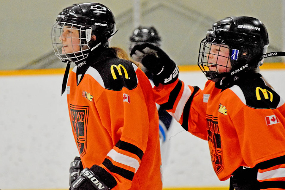Edyn McMartin (right) gives Maia Prest a congratulatory tap on the shoulder after Prest scored in the bronze medal game Sunday morning for Williams Lake Orange en route to a shootout victory. (Greg Sabatino photo - Williams Lake Tribune)