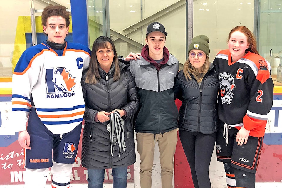 Nyree Alexander (second from left), and her children Ethan and Mackenna, present the silver and gold medals to Kamloops (left) and Salmon Arm (right) during the Williams Lake Minor Hockey Association’s Jeff Alexander Memorial Midget Tournament Sunday. (Amber Camille photo)