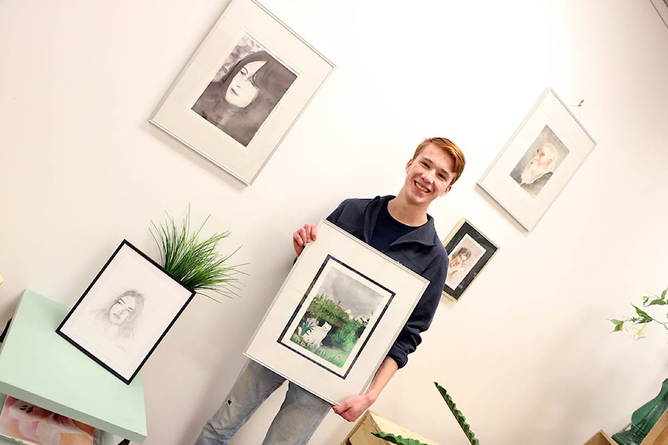 Issac Lauren smiles as he hangs up his artwork at Purple Pansy on Wednesday, March 4 prior to Forseen’s opening on Friday, March 6. (Patrick Davies photo - Williams Lake Tribune)