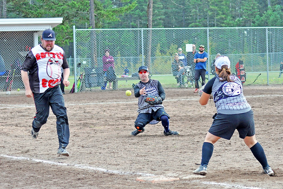 Rowdies pitcher Nick Surette throws to teammate Lesley Allgrove at first base as Rotten Eggs hitter Craig Strayer looks to beat the throw in quarterfinal action Sunday during the Williams Lake Slo-Pitch League’s Year End Tournament at the Esler Sports Complex. The two teams would later square off again in the ‘A’ division final, with the Rotten Eggs marching away the victors. (Greg Sabatino photo -Williams Lake Tribune)