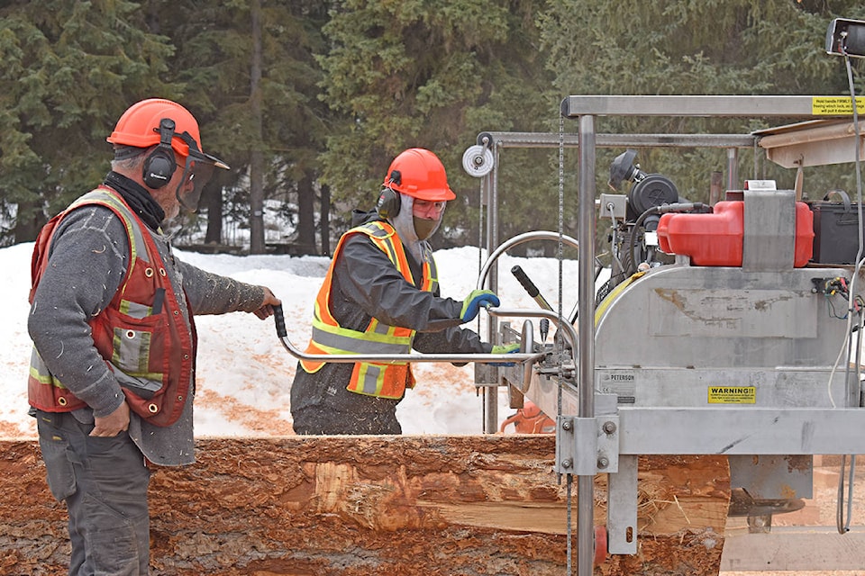 Brian Fuller of Fulltime Ventures (left) guides a participant of a 16-week program at Xat’sull First Nation with operating a swing mill set up at Whispering Willows Campsite. The program got underway last month after being delayed due to COVID-19. (Rebecca Dyok photo)