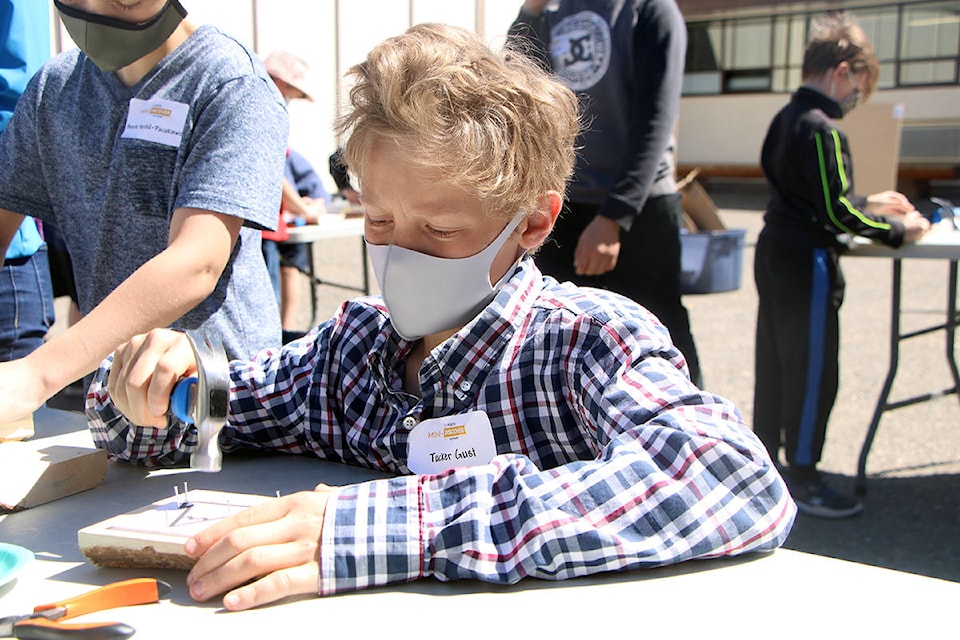 Tucker Gust carefully hammers a nail into a piece of wood in the schoolyard of 100 Mile Elementary. (Patrick Davies photo - 100 Mile Free Press)