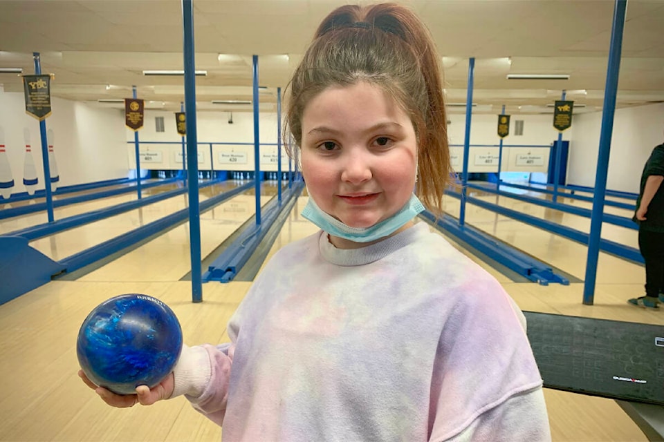 Lily Stewart holds up one of her personal bowling balls as she practices in preparation for playing in the provincial Youth Bowling Council tournament as a bantam.(Ruth Lloyd photo - Williams Lake Tribune)