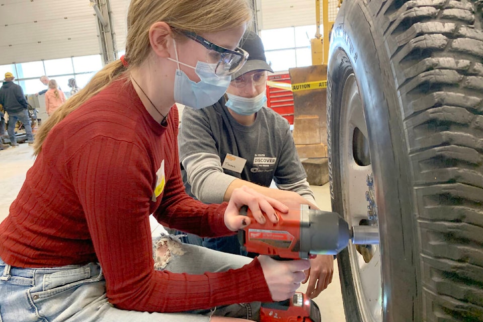 Kristin Fischer was getting her hands dirty removing and replacing some lug nuts on a wheel. She was being shown the ropes by Thomas Burke, a heavy duty mechanic program student at TRU. Fischer said she had considered a job in trades, and was considering studying baking and pastry, but the day opened her up to other ideas. (Ruth Lloyd photo - Williams Lake Tribune)