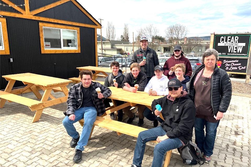 Lake City Secondary School students Noah Friesen, Sebastian Brommit, Josh Oler, teacher Andrew Hutchinson, Cole Rochefort, Ethan Bouchard, Nathan Thomas, Justus Billyboy and Della Rauch of Screamers Ice Cream gather for an ice cream cone around the new benches the students made. (Angie Mindus photo - Williams Lake Tribune)
