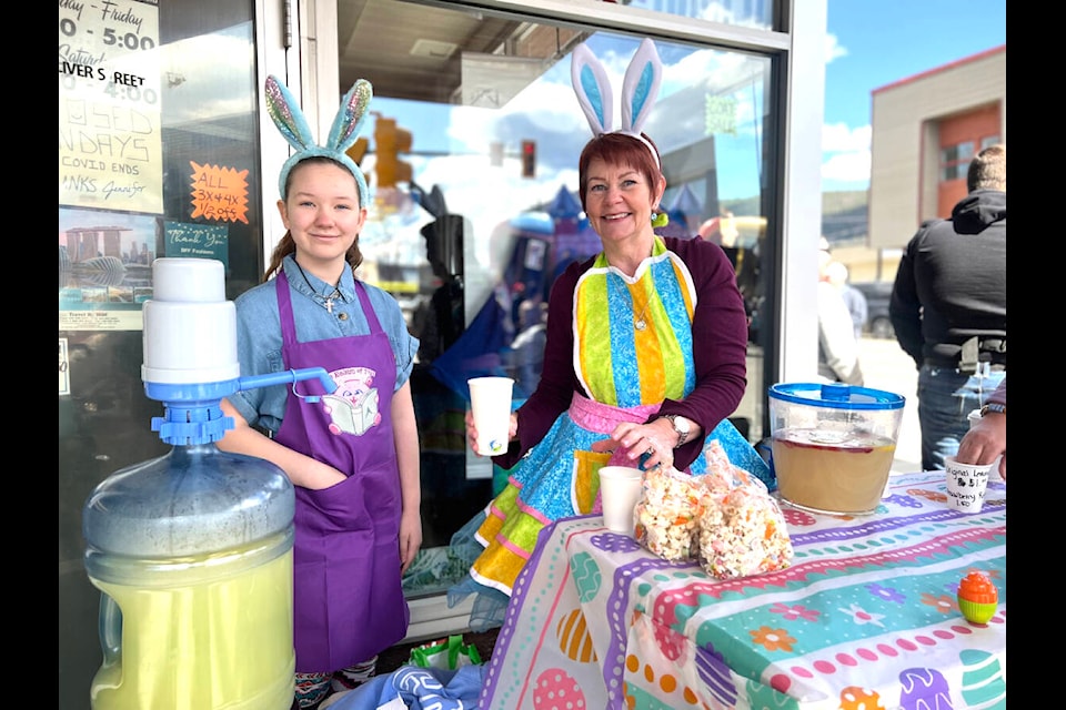 Raelyn Howarth, 9, mans her lemonade booth outside Realm of Toys Sunday afternoon with a little help from Joan Douillard. (Angie Mindus photo - Williams Lake Tribune)