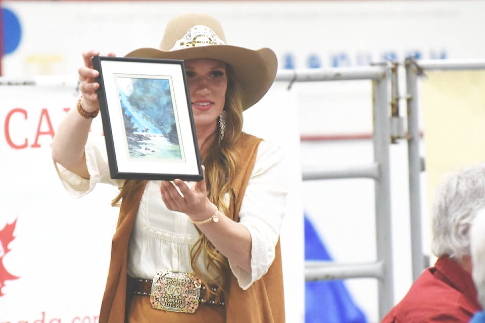 Williams Lake Stampede Princess Kennady Dyck shows potential bidders a framed picture up for auction. (Angie Mindus photo - Williams Lake Tribune)