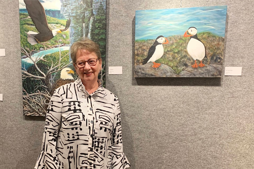 Artist Anne Brown stands next to her painting of puffins at the Station House Gallery on June 2, 2022 for the opening night reception of the group show Wind, Wings & Distractions. (Ruth Lloyd photo - Williams Lake Tribune)