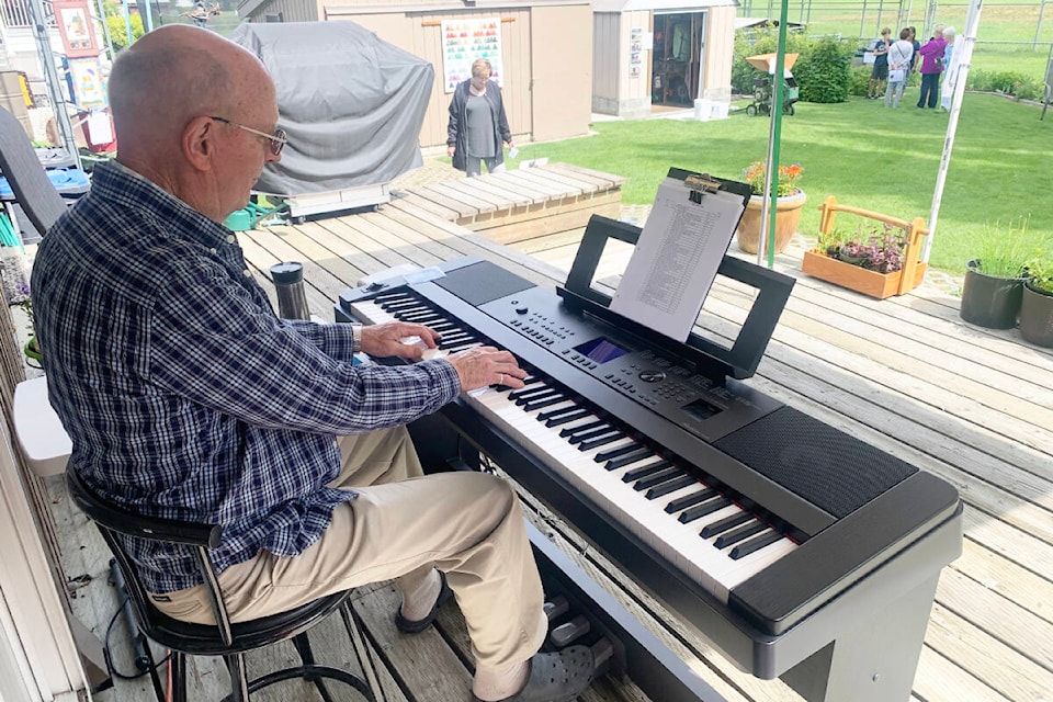 Hal Giles played some tunes for the garden tourists visiting his yard on July 9. (Ruth Lloyd photo - Williams Lake Tribune)