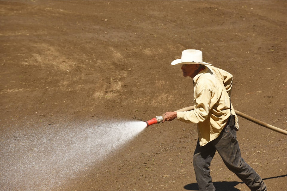 Doug Johnson wets down the rodeo grounds before the events get underway. (Ruth Lloyd photo - Williams Lake Tribune)