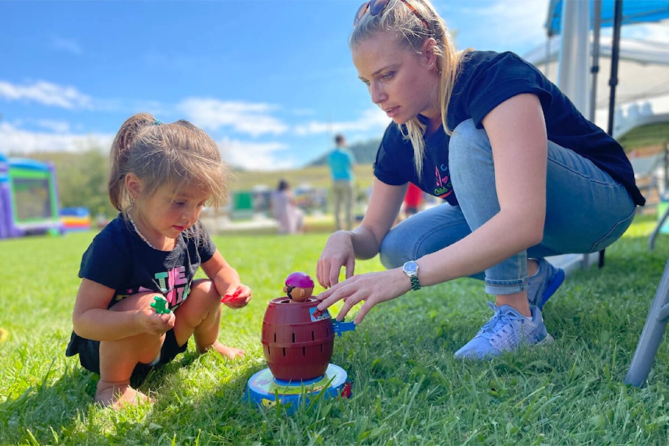 Gracie-Lynn Sellars, left, was getting a helping hand with a game from Courtney de Villiers, speech and learning pathologist with the Cariboo Chilcotin Child Development Centre at the WLFN block party event on Aug. 26. (Ruth Lloyd photo - Williams Lake Tribune)