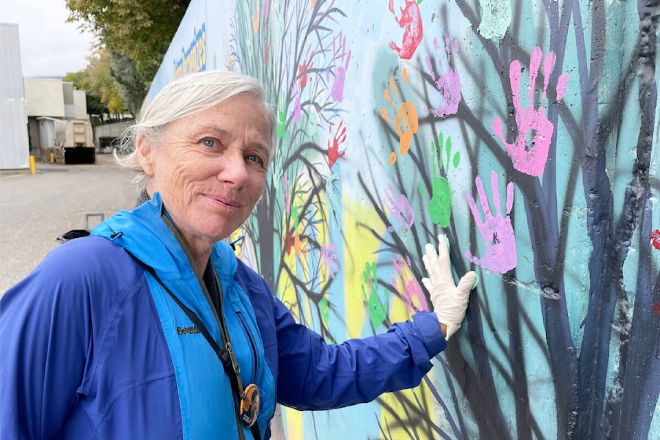 Denise Deschene adds her helping hand to the Rotary mural on Sept. 10, 2022. (Ruth Lloyd photo - Williams Lake Tribune)