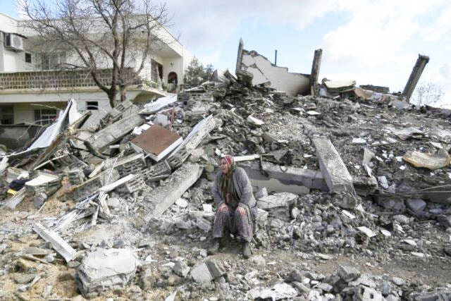 A woman sits on the rubble as emergency rescue teams search for people under the remains of destroyed buildings in a city in southern Turkey, on Tuesday, Feb. 7, 2023. White Rock deputy fire Chief Norm MacLeod has joined efforts to assist in the devastated country, as part of a Burnaby Urban Search and Rescue team. (Photo by Khalil Hamra, the Canadian Press/Ap)