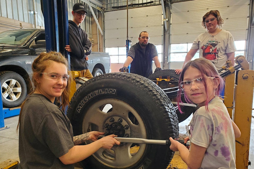 TRU heavy mechanical foundation student Karli-Rae Roussel, left, collaborates with Grade 7 student Amelia Chalifoux to repair a tire. (Monica Lamb-Yorski photo - Williams Lake Tribune)