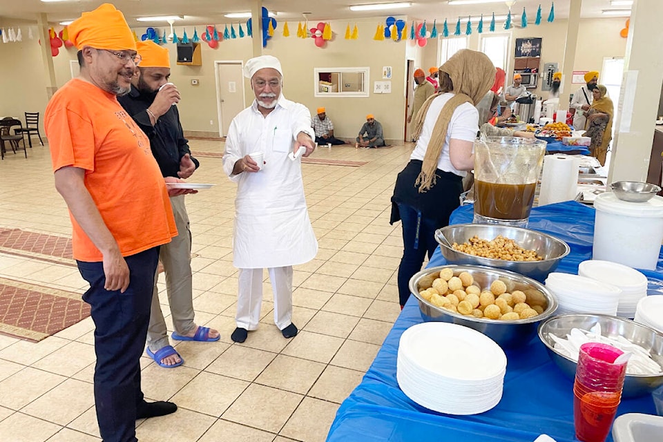Mayor Surinderpal Rathor, centre, points out some of the different dishes to Councillor Michael Moses, front left, at Vaisakhi celebrations at Gurdwara Sahib Western Singh Sabha Association on May 13, 2023. (Ruth Lloyd photo Efteen)