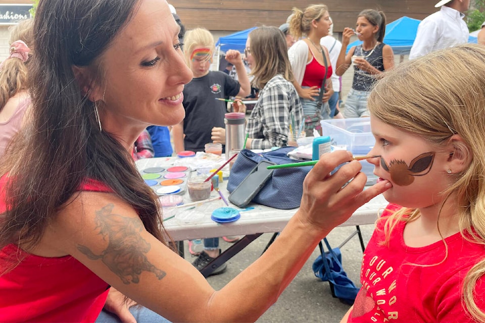 Tiffany Jorgensen, left, of Cariboo Art Beat, paints Sophia Wilson’s face, during the Summer Street Fest events in downtown Williams Lake. (Ruth Lloyd photo - Efteen)