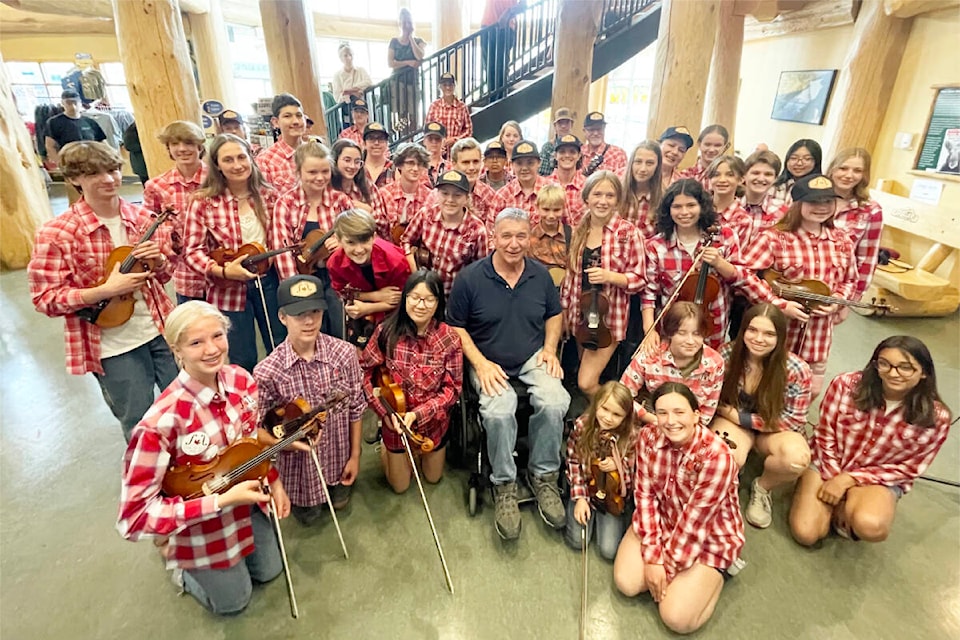 Rick Hansen poses for a photo with the Cariboo Chilcotin Youth Fiddle Society and some of their Nova Scotia fiddle exchange students after the young musicians performed St. Elmo’s Fire for him at the opening of the exhibit. (Ruth Lloyd photo - Williams Lake Tribune)