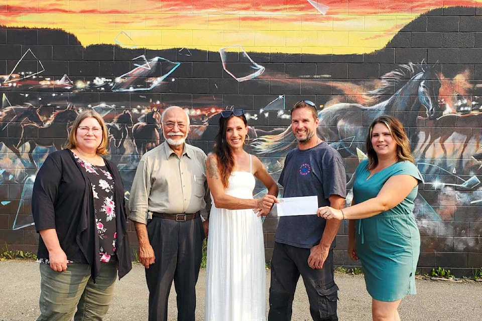 Sherry Yonkman, Downtown Williams Lake BIA executive director, left and Mayor Surinderpal Rathor present a public art grant to artists Tiffany Jorgensen, centre and Sarah Sigurdson, right, for the mural they created for Stampede Glass owner Brian Doering, second from right. (Monica Lamb-Yorski photo - Efteen)