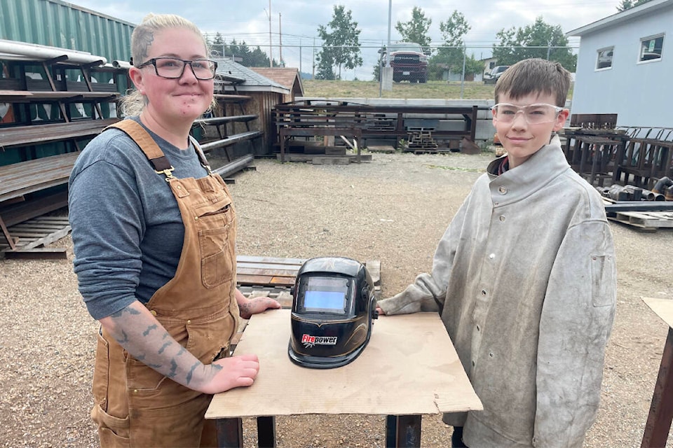 Teri Christiansen, of 100 Mile House, is a welder who returned to her alma mater of TRU Williams Lake to help out as a volunteer welding instructor for the Mind Over Metal welding camp July 24-28. She was helping student Benjamin Behan figure out fixing his welding helmet on their last day of the camp. (Ruth Lloyd photo - Williams Lake Tribune)