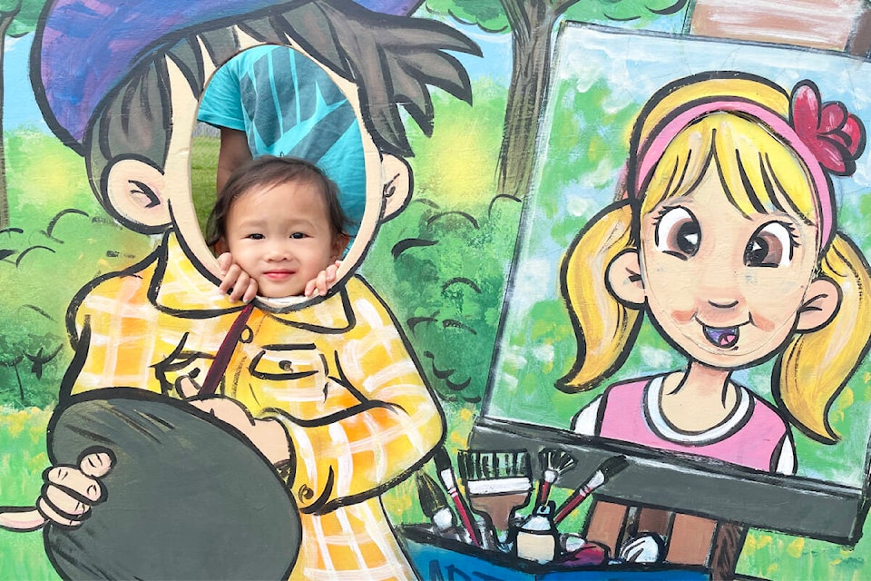 Calliope Galvez, one and a half, was having fun peeking through the photo op cut outs at the Downtown Williams Lake Art Walk booth at the Williams Lake Farmers’ Market on Aug. 11, 2023. (Ruth Lloyd photo - Efteen)