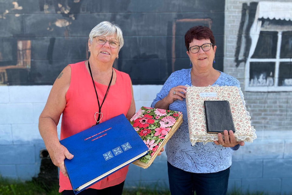 Marg Bublitz (L) and Judy Newbery are volunteers with the Cariboo Memorial Hospital Auxiliary, currently made up of 21 active members. Newbery is the president of the group, which is celebrating its hundredth year. The two stopped into the Tribune office to show the record-keeping maintained by the group for the last hundred years. (Kim Kimberlin/Efteen, Aug. 2023)