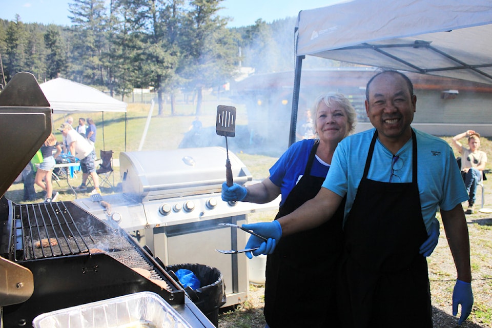 Alison Sutherland-Mann (back) and Nic Suapa (front) flipping burgers at Thompson Rivers University's annual welcome barbecue. 