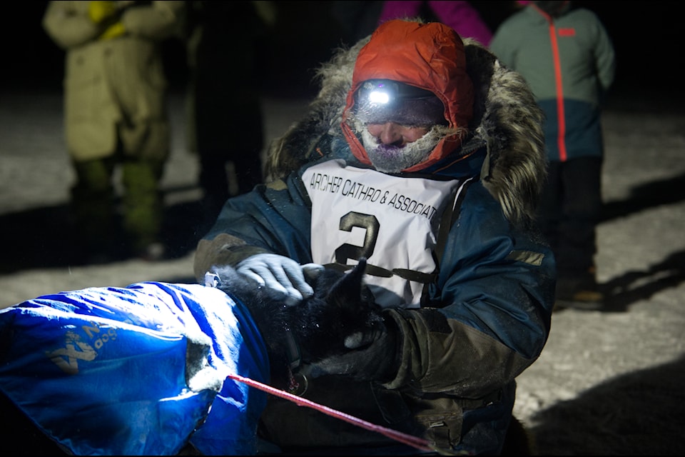 Michelle Phillips gives her team of dogs some praise and hugs after crossing the finish line at Teslin Bridge on Feb. 5. (Jake Howarth/Yukon News)