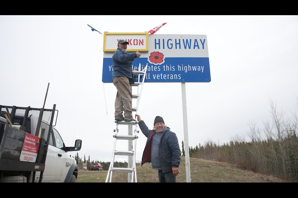 Leo Martel (on the ladder) and Richard Fontaine placed placcards on bearing their preferred name for the Alaska Highway on a series of Alaska Highway signs near Whitehorse on May 12. (Jim Elliot/Yukon News)
