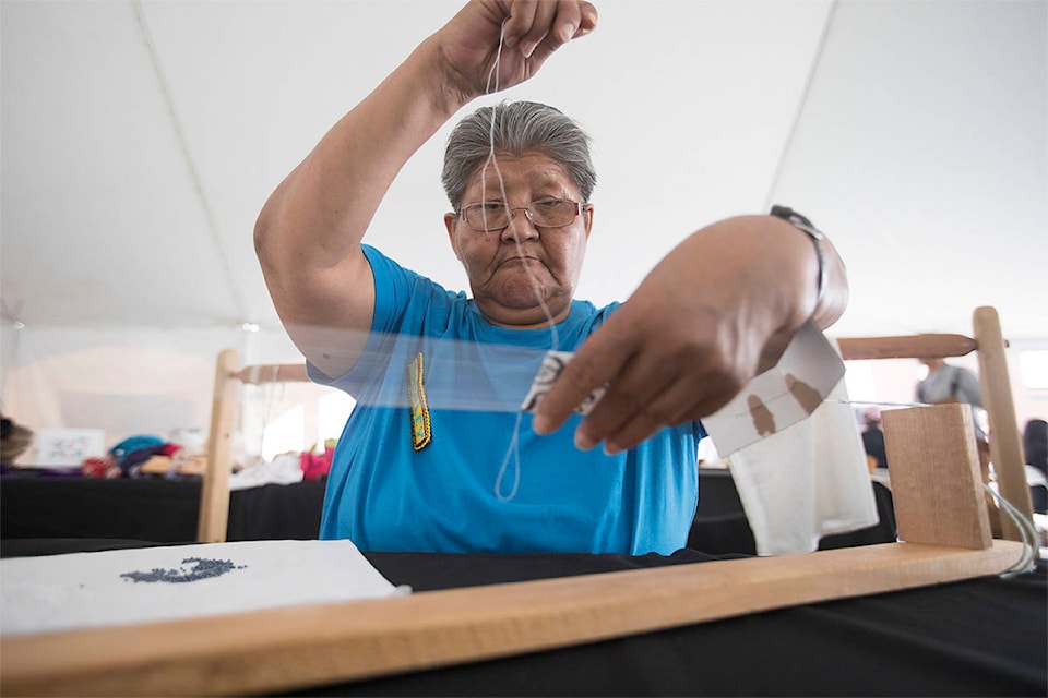 Shirley Kakfwi, Vuntut Gwitchin First Nation from Old Crow, does bead looming during the Adäka Cultural Festival in Whitehorse on July 1, 2019. (Crystal Schick/Yukon News)