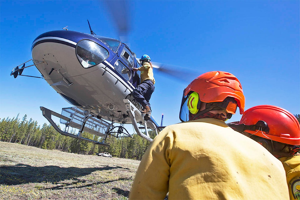 A Whitehorse wildland firefighting crew watches as their crew leader exits a hovering helicopter during training near Chadburn Lake on May 22. (Crystal Schick/Yukon News)