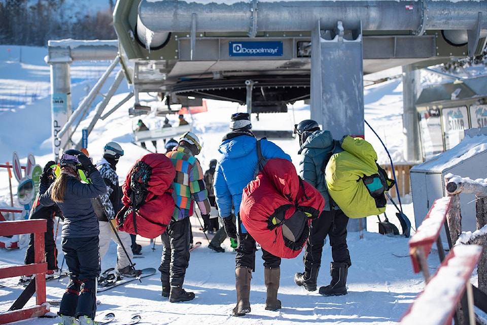 Paragliders Russell Bamford, Sam Bamford and Trevor Mead-Robins approach the chairlift at Mount Sima in Whitehorse on February 13, 2021. (Haley Ritchie/Yukon News)