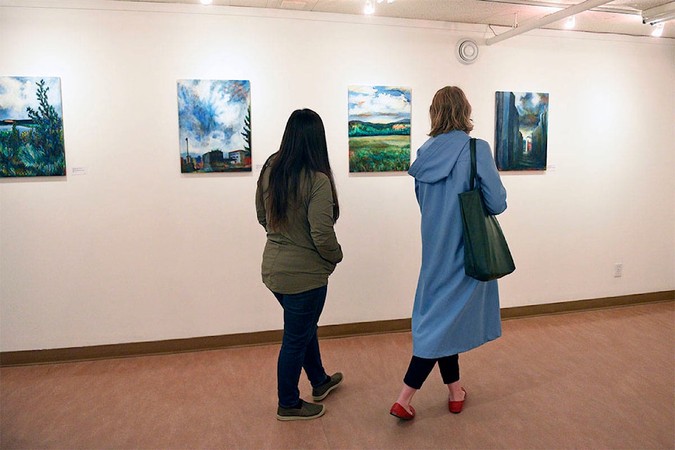 Two gallery visitors admire Natasha Henderson’s Yukon landscapes in the Focus Gallery on Aug. 12. (Haley Ritchie/Yukon News)