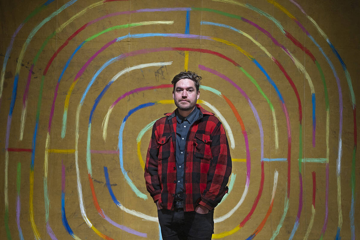 Joseph Tisiga stands in front of one of his art pieces in the Yukon Prize finalists exhibit after winning the $20,000 prize during the Yukon Prize for Visual Arts Gala at the Yukon Arts Centre on Nov. 20. (Mike Thomas/Yukon Arts Centre)