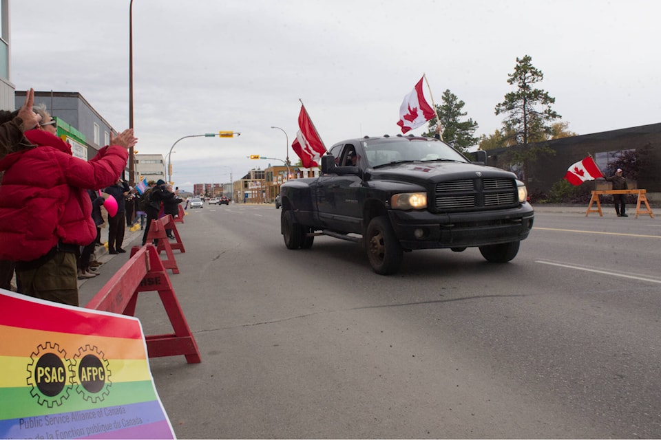 A truck flying two Canadian flags speeds past demonstrators counter-protesting the “Million March 4 Children” outside the Yukon legislature on Sept. 20. (Matthew Bossons/Yukon News)